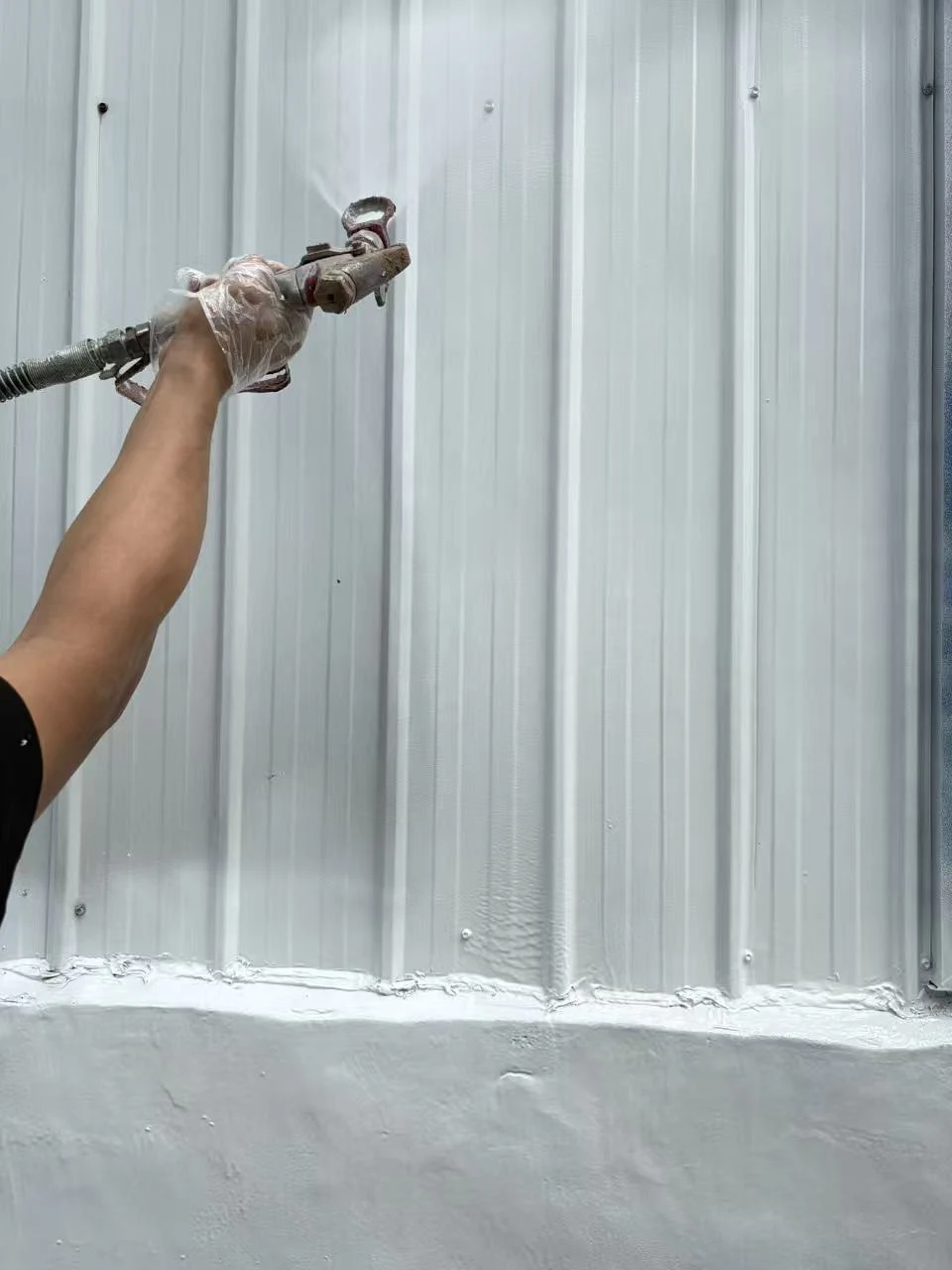 Splasher sprays white paint on the surface of the bellows.